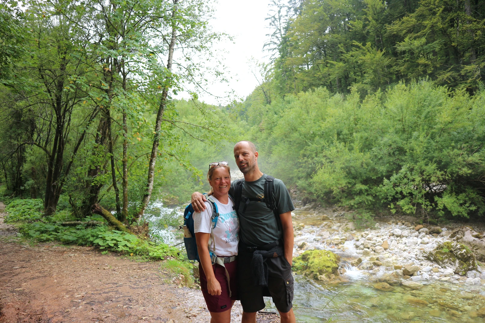 Een foto van Jeroen en Mirjam voor een rivier. Ze dragen wandelkleding, en overal om hun heen staan bomen.